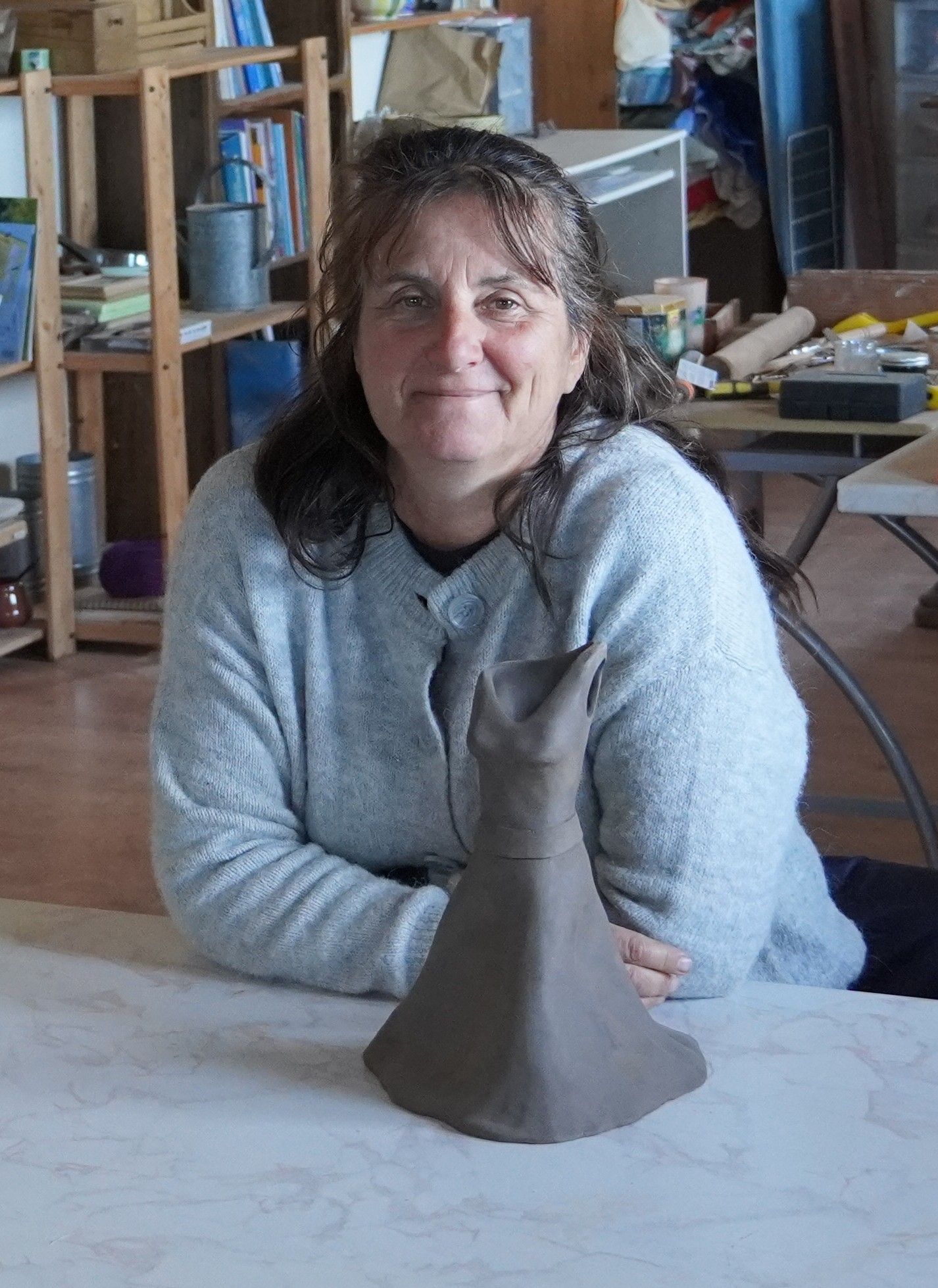 Portrait de Christine dans son atelier avec une robe en terre non cuite devant elle